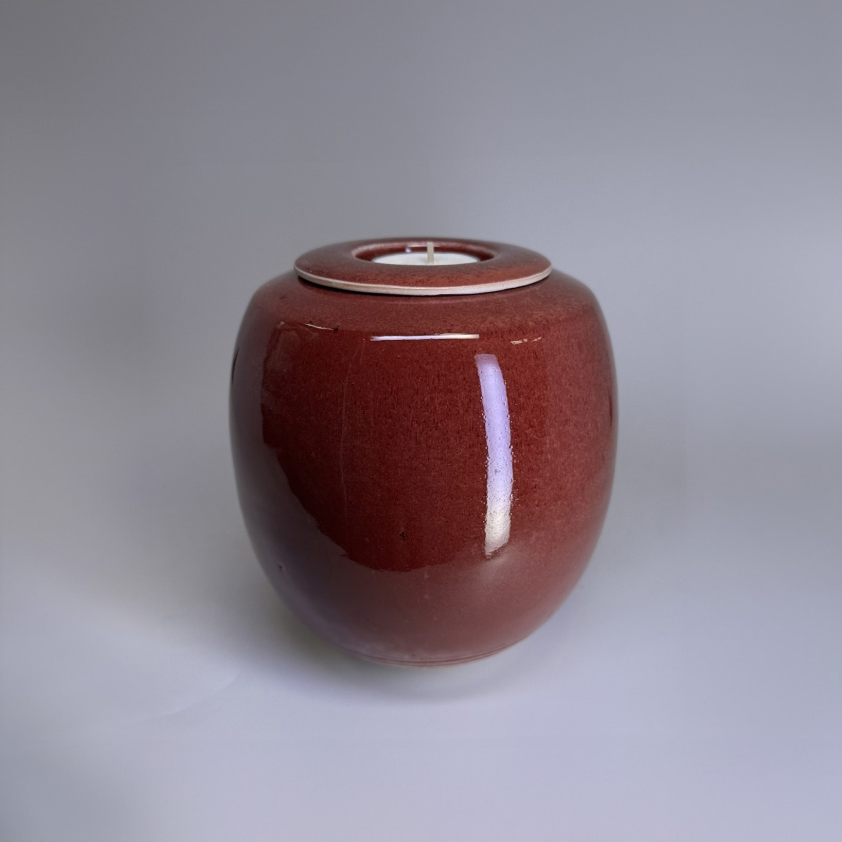 Handmade ceramic memorial urn in ember red with smooth glossy finish and rounded form