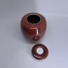 Small ceramic urn with removable candle holder lid shown separately in ember red glaze