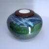 Evergreen ceramic cremation urn with forest green and blue layered glaze and wooden candle holder