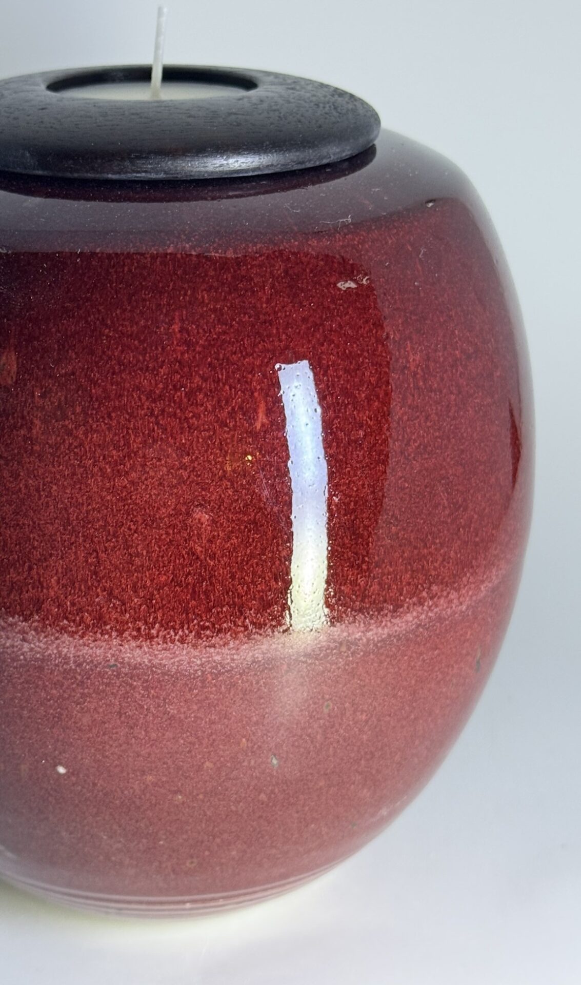 Close-up of Flame cremation urn showing textured red glaze detail and candle holder