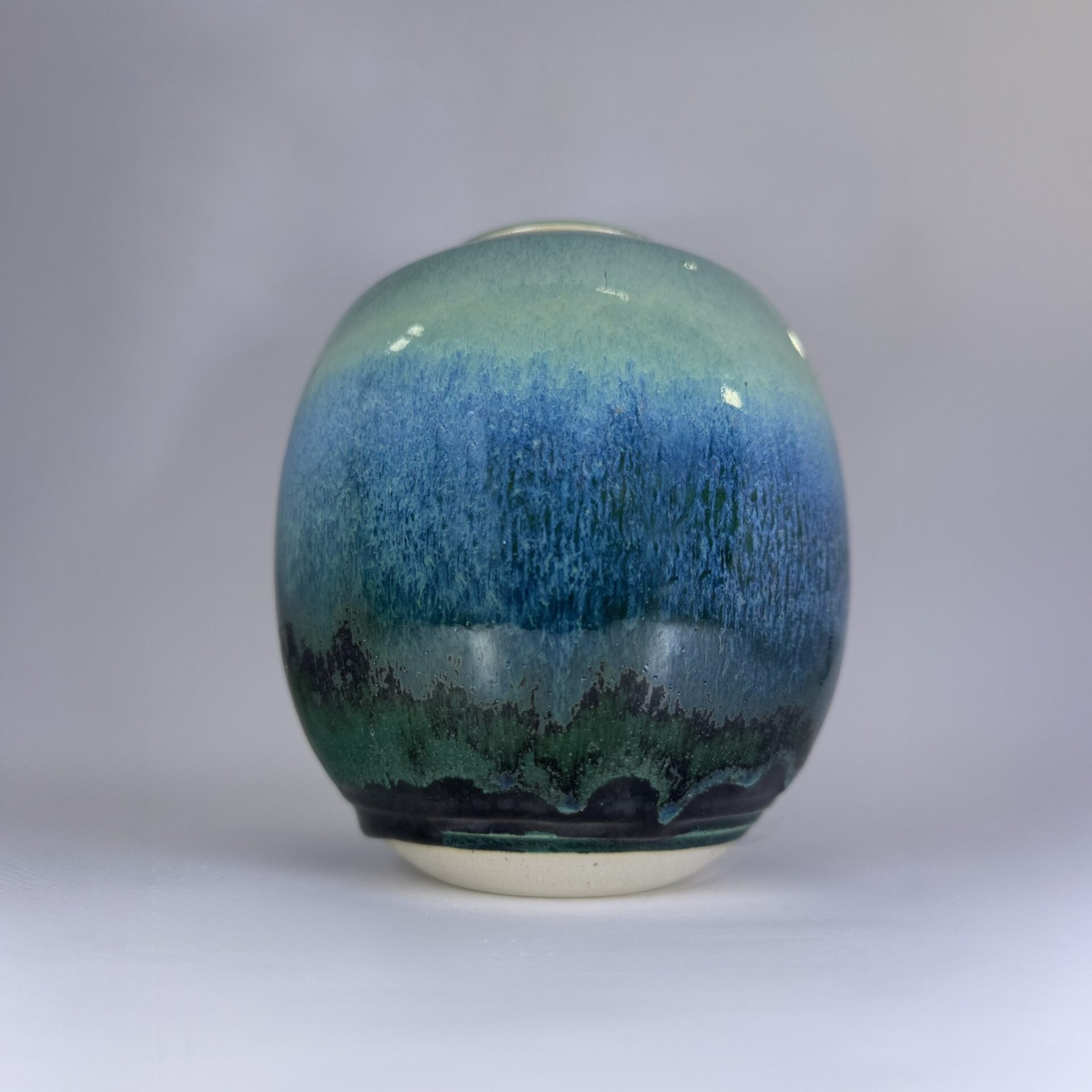 Small cremation urn showing detailed blue green gradient glaze with textured finish