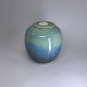 Handmade small cremation urn in ocean-inspired teal and blue gradient glaze