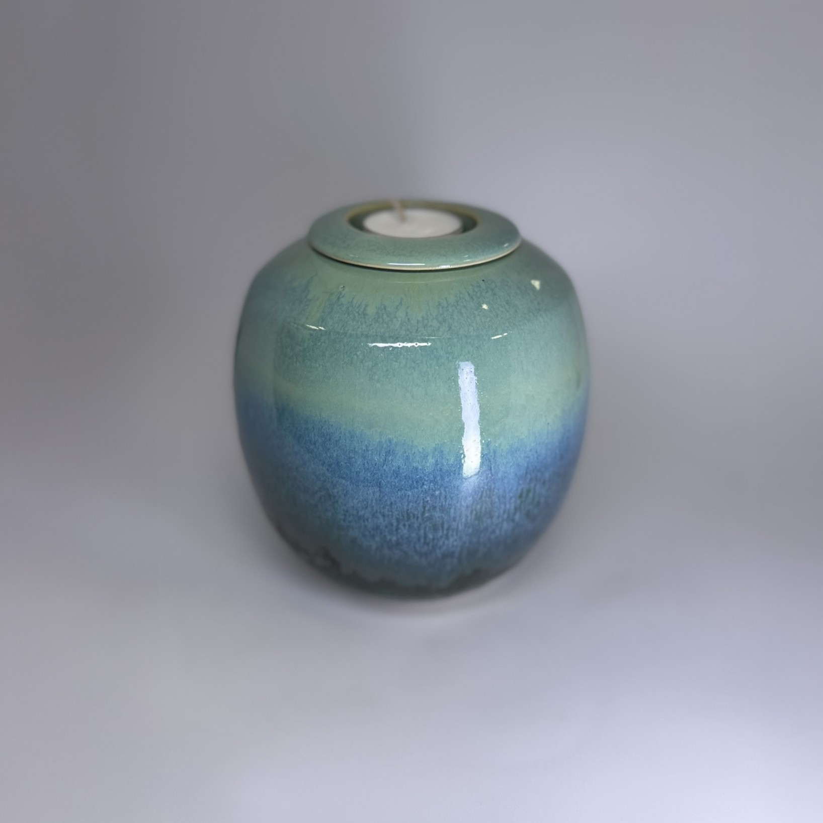 Handmade small cremation urn in ocean-inspired teal and blue gradient glaze